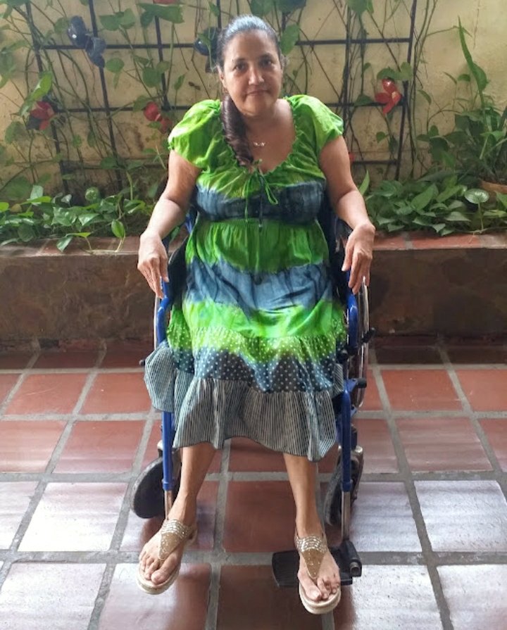 A woman seated in a new wheelchair in a courtyard